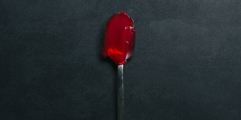 A spoon with red jelly 