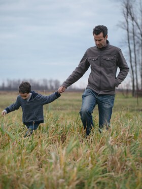 Mark Schatzker and his son walking through a grassy field