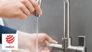 A man safely touch the spout while the tap is pouring boiling water